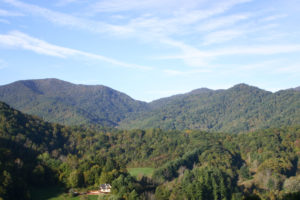 Mountains with blue sky and small pops of yellow and orange