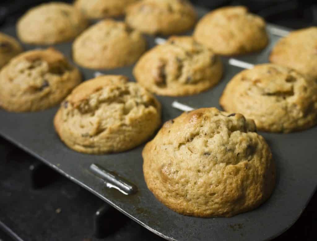 Muffins in an aluminum pan at an angle apparently coming out of the oven. 