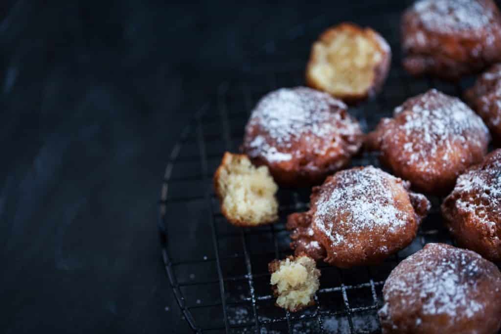 Dark fried apple fritters on right half of frame on dark background