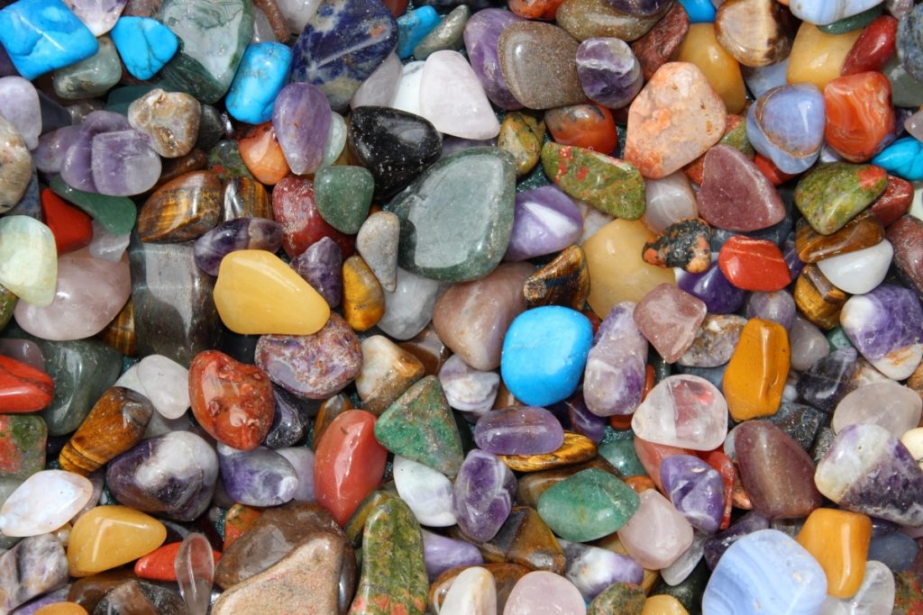 Shiny rocks, all colors and shape fill the frame. One looks like blue robin egg is near center.
