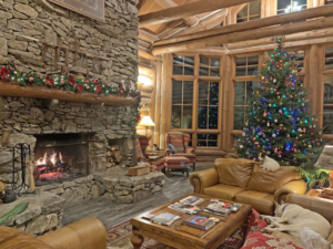 Large stone fireplace with warm fire, vaulted ceilings, cozy furniture and christmas tree