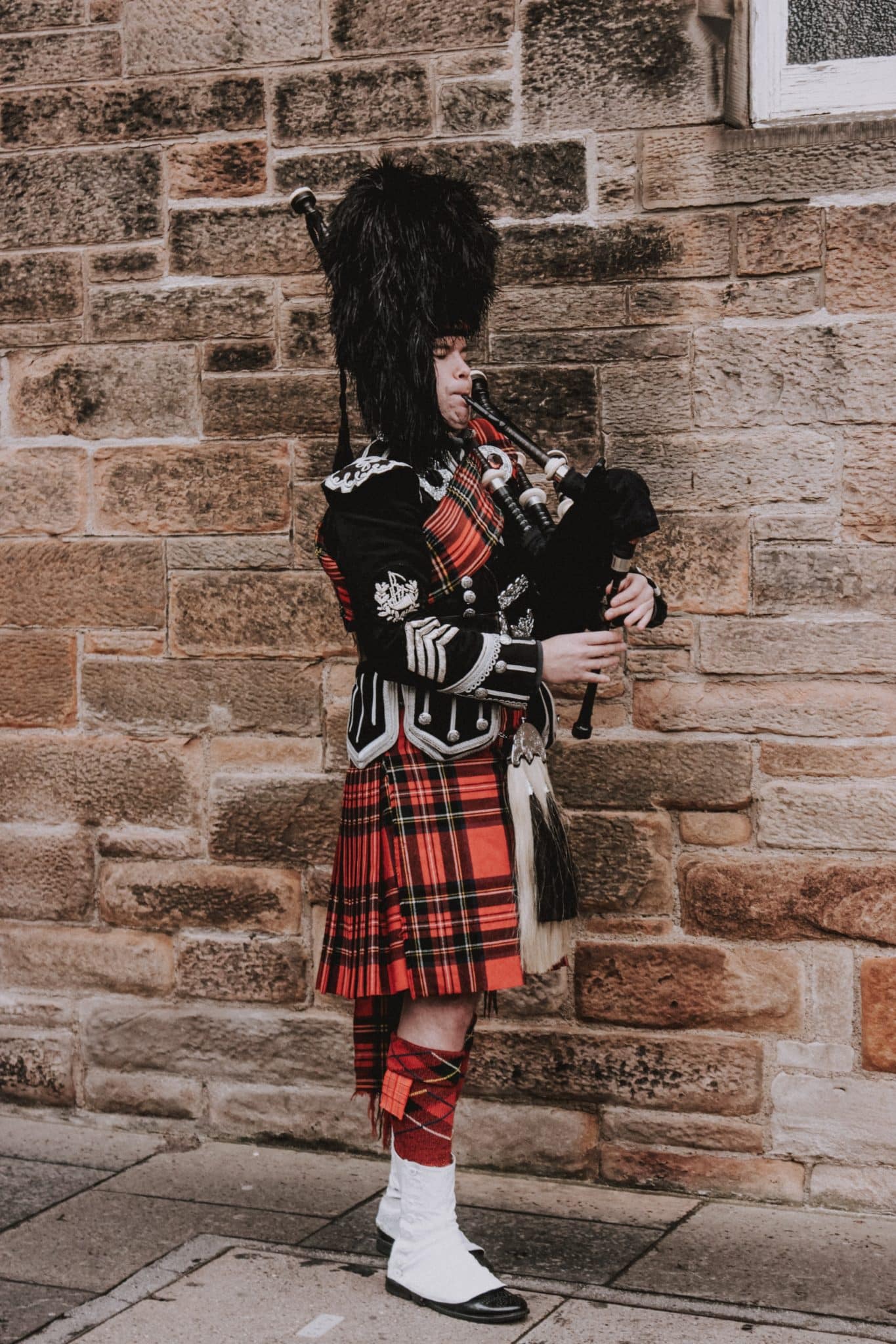 Male bagpiper dressed in Scottish garb with kilt