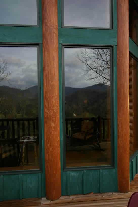 Large windows between cedar logs on exterior of home..