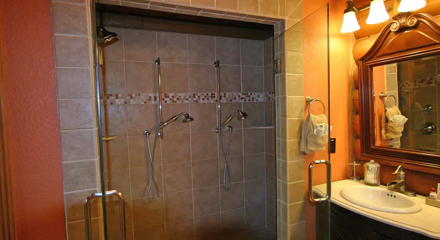 Custom shower enclosure with multiple shower heads in bathroom. 