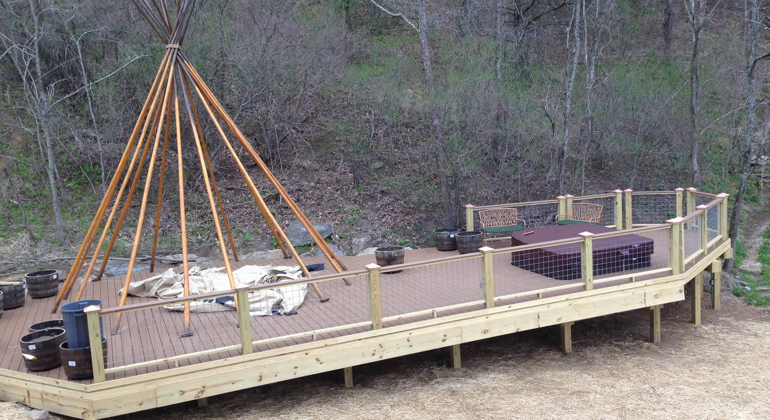 Bare poles of a wigwam on a long deck outside. 