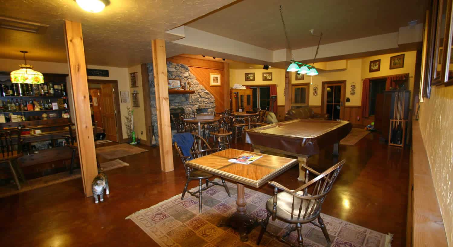 Game room with a pool table , games table, bar and fireplace. 