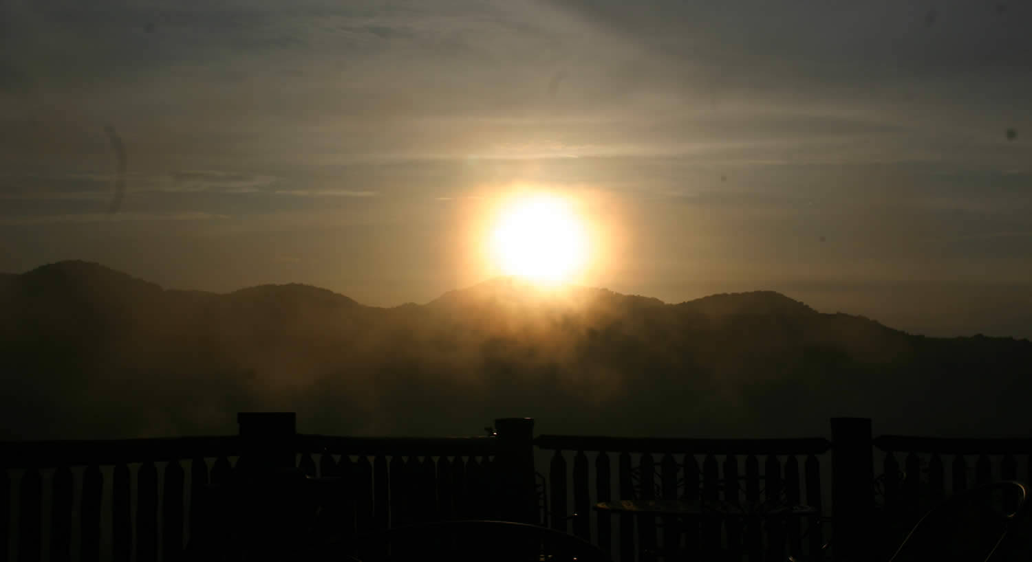 The sun rising over the mountains through the mist. 