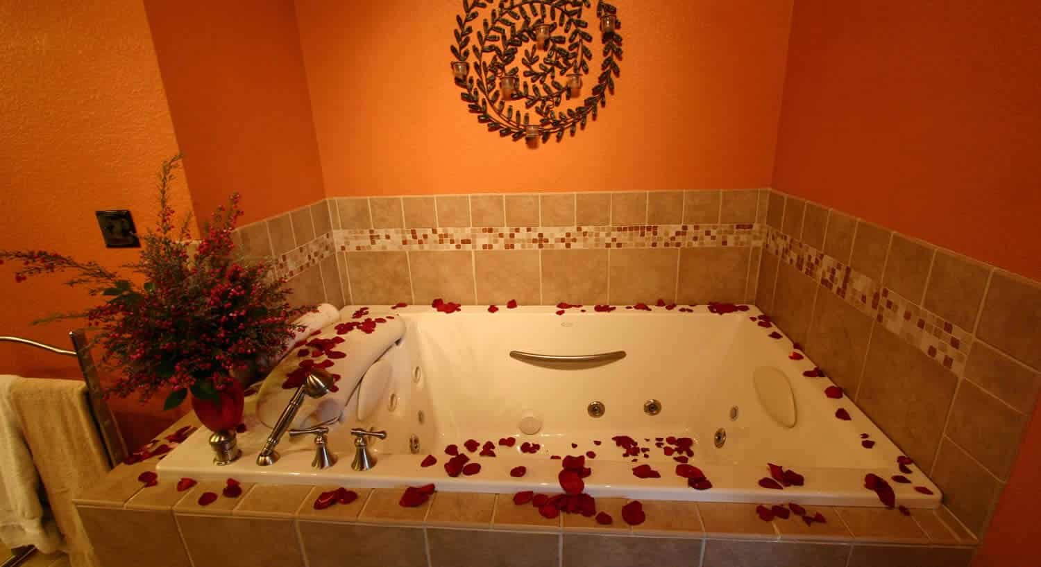 Large whirlpool bath surrounded by scattered rose petals 
