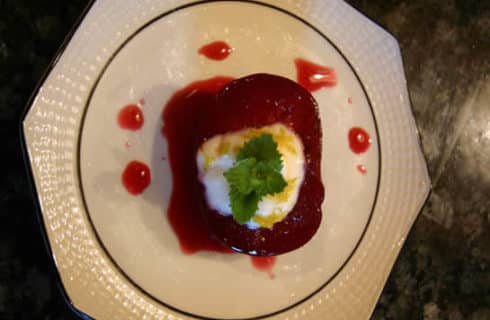 Red jellied dessert with meringue topping on a white plate.