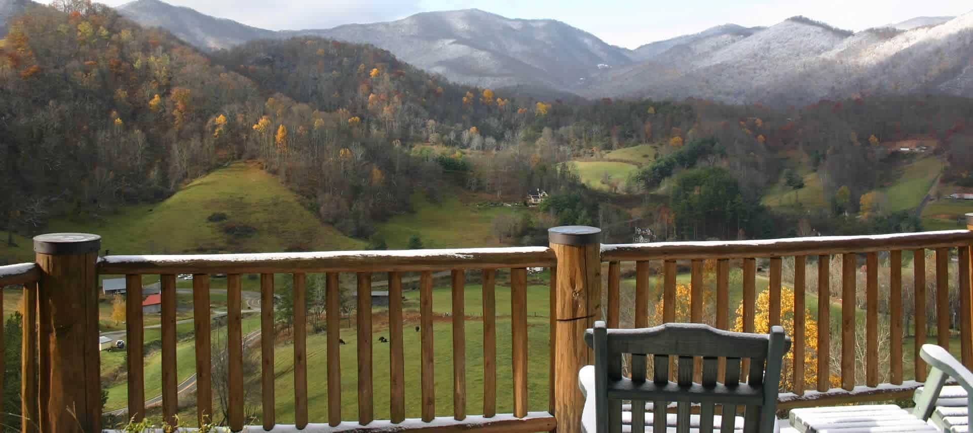 View from wooden balcony of fields and hills and further mountains. 