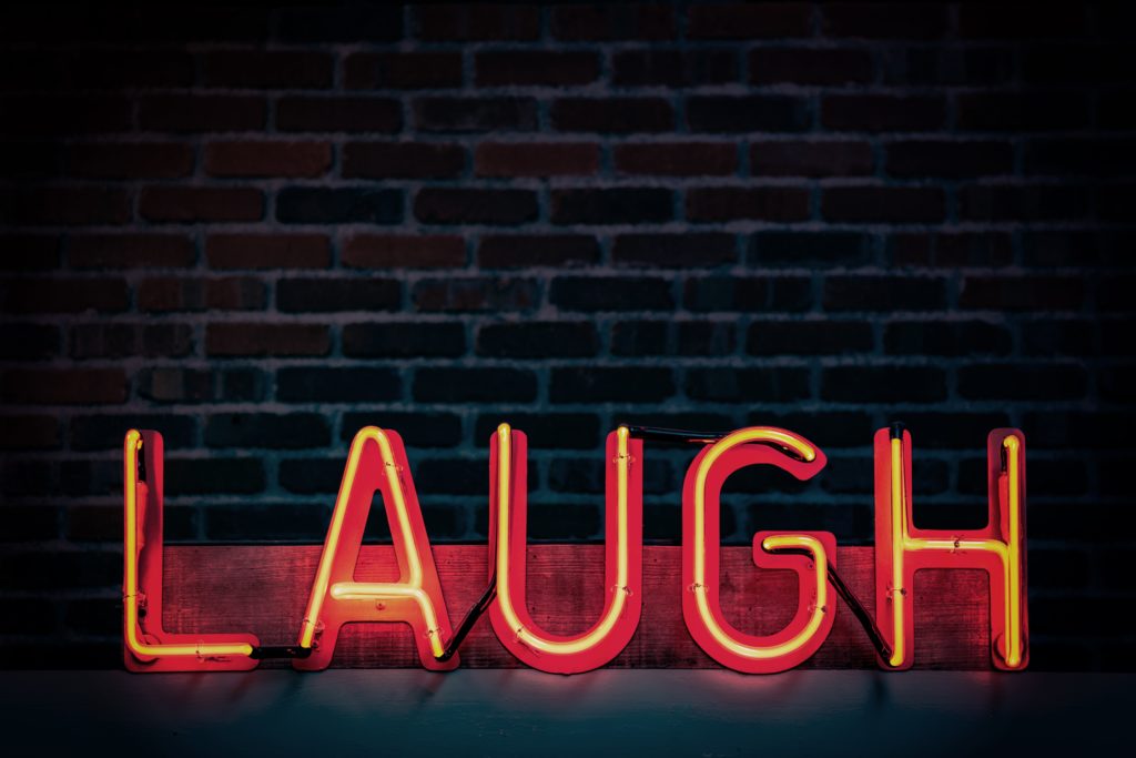 Red neon sign that says, "LAUGH"