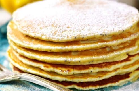 Blue plate topped with a stack of lemon pancakes dusted with powdered sugar