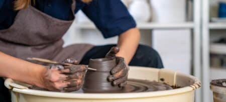 A person works a pottery wheel, putting detail on a spinning bowl.