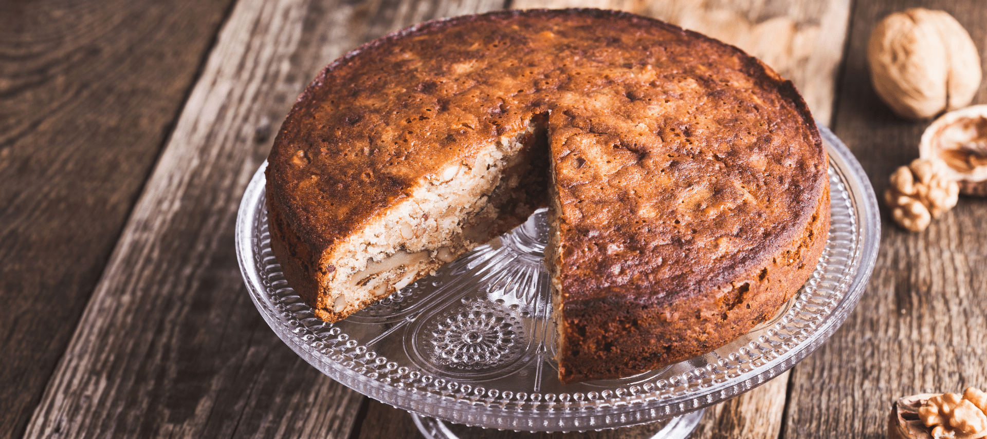 walnut cake on a cake stand with a slice removed