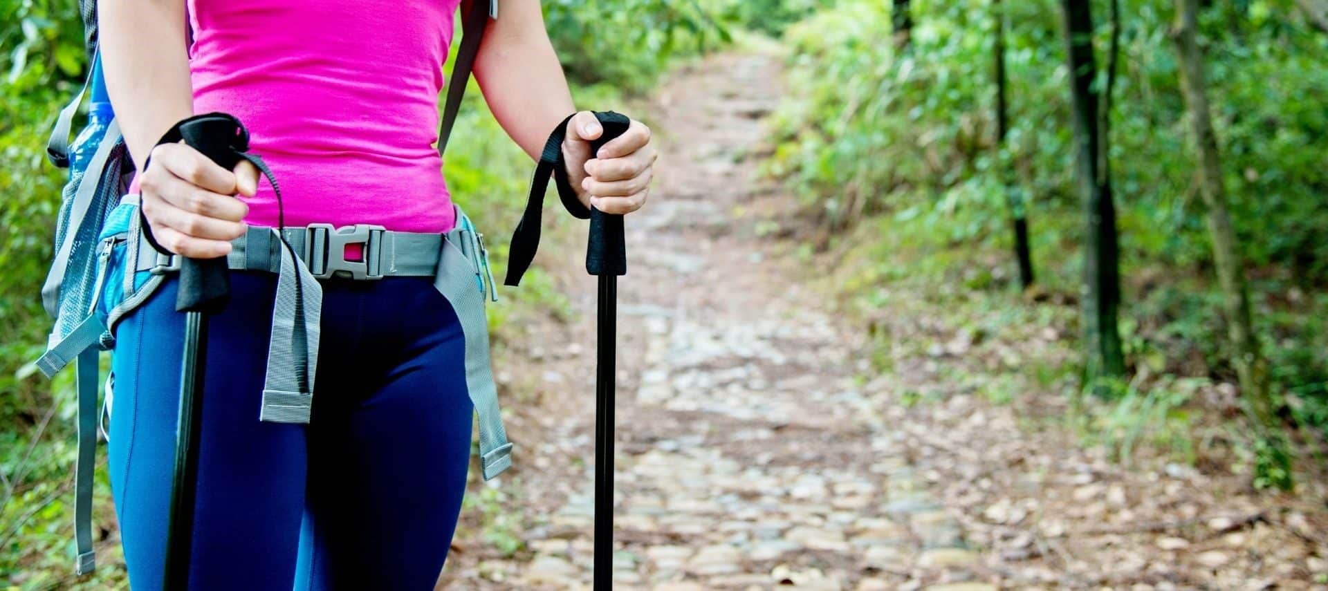 Woman hiking in a forest with a backpack and gripping hiking poles