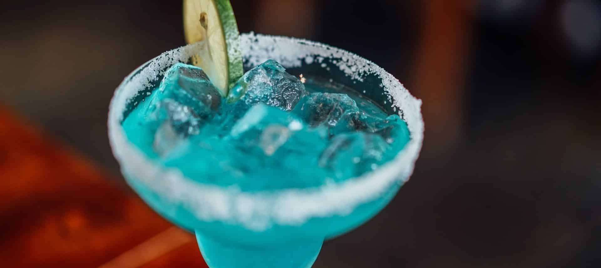 Blue margarita with sugar on the rim and a lime slice on the edge of the glass