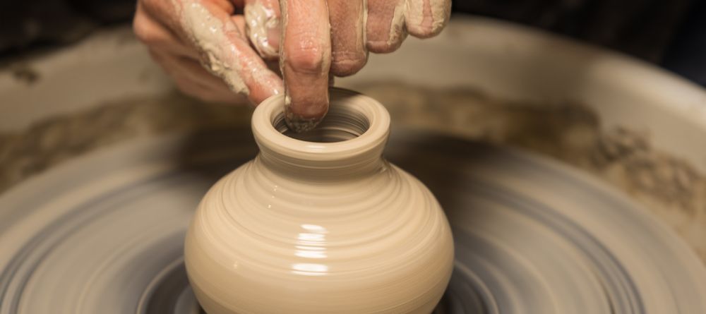 A potter creating a ceramics piece on a potter’s wheel